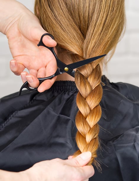 Femme aux cheveux longs tressés qui fait un don de cheveux