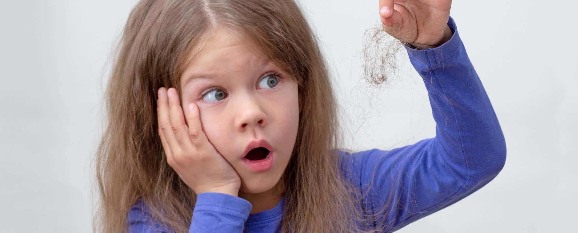 Fillette qui perd ses cheveux et tient des cheveux dans sa main