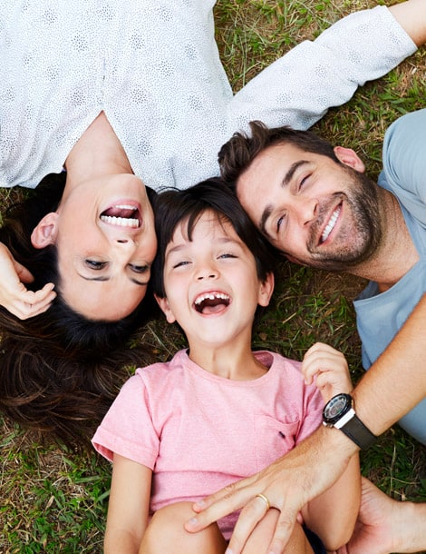 Mère, père et fillette souriants et couchés sur le sol