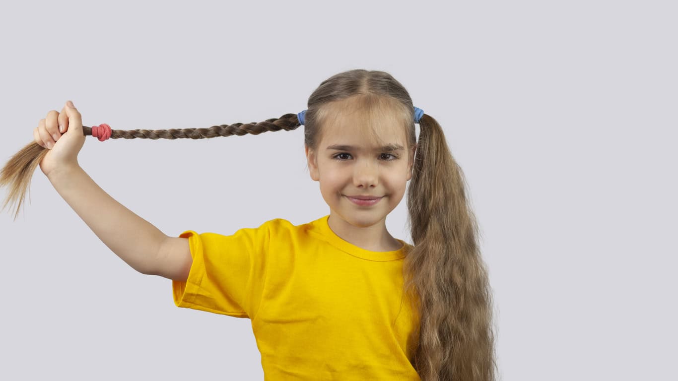 Fillette qui attache ses cheveux pour prévenir les poux de tête.