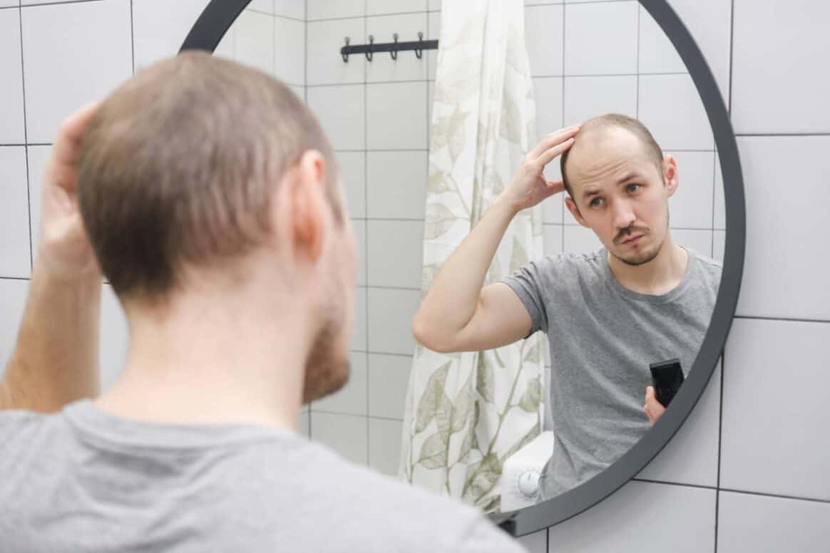 Un homme préoccupé par sa perte de cheveux s’observe dans le miroir