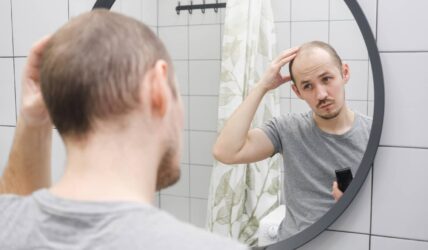 Un homme préoccupé par sa perte de cheveux s’observe dans le miroir